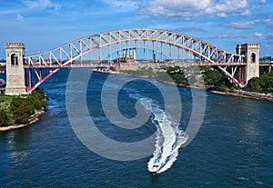 Powerboat leaves a wake as it drives under the Hell Gate Bridge