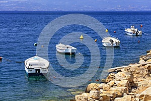 Powerboats and boats are anchored along the rocky coast of the Ionian Sea