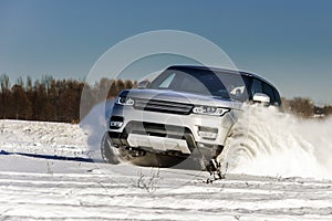 Powerful 4x4 offroader car running on snow field