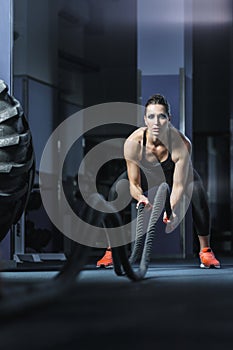 Powerful attractive muscular CrossFit trainer do battle workout with ropes