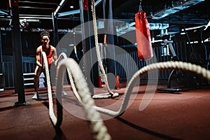 Powerful attractive muscular woman battle rope workout at the gym