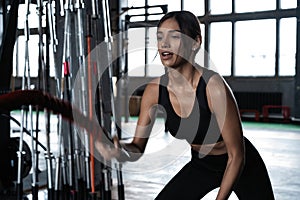 Powerful attractive muscular woman CrossFit trainer do battle workout with ropes at the gym