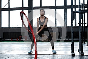 Powerful attractive muscular woman CrossFit trainer do battle workout with ropes at the gym