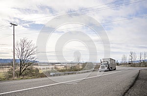 Powerful big rig semi truck tractor transporting fuel in long tank semi trailer climbing on up hill road