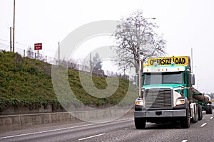 Powerful big rig semi truck transporting oversize load on the in