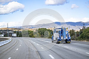 Powerful big rig towing semi truck tractor with lifting boom running on the wide highway road to help a semi truck in an accident