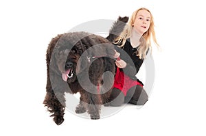 Powerful black labradoodle on a red leash pulling happy, young blonde girl along