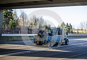 Powerful blue big rig tow semi truck with boom and other towing equipment