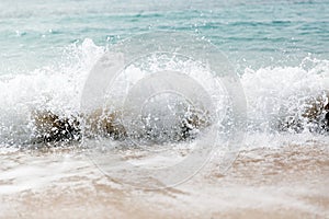 Powerful blue wave breaks along the shore. Close up