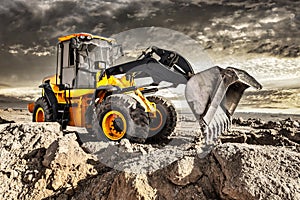 Powerful bulldozer or loader moves the earth at the construction site against the sky. An earthmoving machine is leveling the site