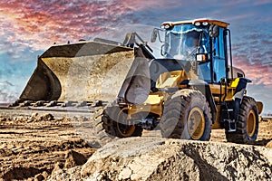 Powerful bulldozer or loader moves the earth at the construction site against the sky. An earthmoving machine is leveling the site