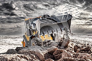 Powerful bulldozer or loader moves the earth at the construction site against the sky. An earthmoving machine is leveling the site