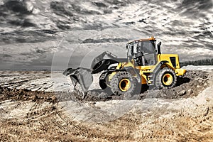 Powerful bulldozer or loader moves the earth at the construction site against the sky. An earthmoving machine is leveling the site