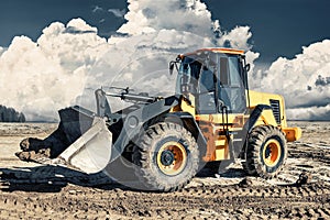 Powerful bulldozer or loader moves the earth at the construction site against the sky. An earthmoving machine is leveling the site