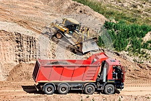 A powerful bulldozer in a sand pit is planning a site. Extraction of sand in an open pit. natural building materials