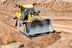 A powerful bulldozer in a sand pit is planning a site. Extraction of sand in an open pit. natural building materials