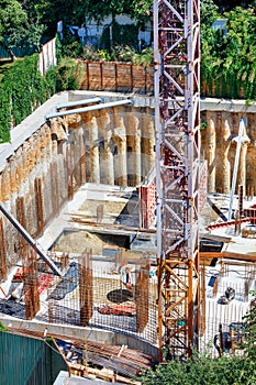 Powerful construction of the foundation of a new building with a fragment of a tower crane body on a summer day