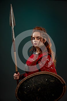 Powerful female fighter in armor keeping spear and shield