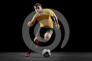 Powerful, flying above the field. Young football, soccer player in action, motion isolated on black studio background .