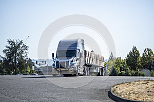 Powerful gray big rig semi truck with loaded by lumber flat bed semi trailer standing on the industrial parking lot take a break