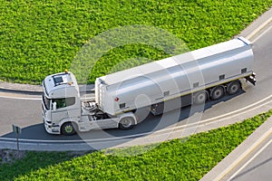 Powerful heavy white truck with a tank for flammable liquids rides turn on the road, close up view