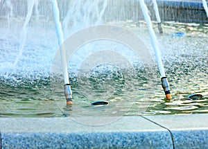 Powerful jets of water in a city fountain made of polished granite burst from metal nozzles