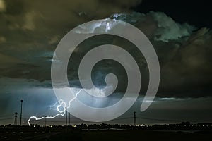 A powerful lightning bolt strikes in the earth from a dramatic thundercloud.