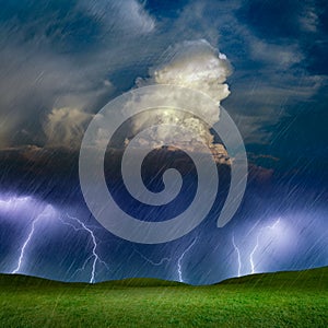 Powerful lightnings in dark stormy sky above green grass hills