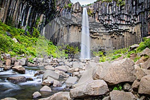 Powerful and magestic waterfall with volcanic rock in an Icelandic landscape