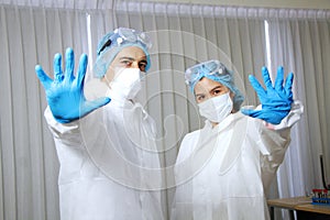 Powerful of Medical team in Personal Protective Equipment or PPE clothing and Healing for patient and showing stop hand sign for