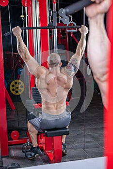 Powerful muscular man doing exercise for back on the lat machine