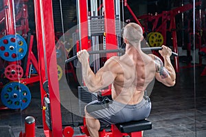 Powerful muscular man doing exercise for back on the lat machine