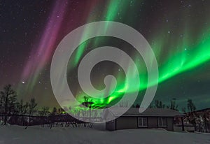 Powerful northern lights above a cabin