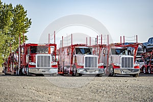 Powerful professional classic big rigs car hauler semi trucks with modular semi trailers standing in row on the business parking