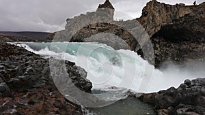 Powerful raging whitewater waterfall falling forcefully over a rocky edge. Crystal clear glacier water stream dropping over the cl