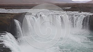 Powerful raging whitewater waterfall falling forcefully over a rocky edge. Crystal clear glacier water stream dropping over the cl