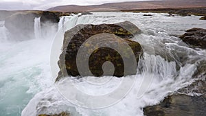 Powerful raging whitewater waterfall falling forcefully over a rocky edge. Crystal clear glacier water stream dropping over the cl