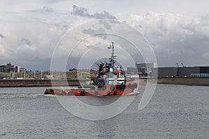 Powerful red color tugboat getting back to the harbor photo