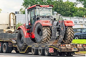 Powerful red tractor on a platform trailer road transportation
