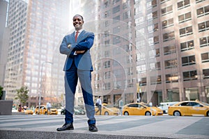 Powerful stance portrait of a successful and accomplished African American CEO businessman, in financial district with city skyscr