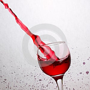 Powerful stream of red wine flew from a tilted glass