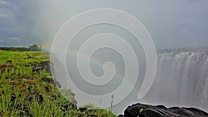 Powerful streams of Victoria Falls crash into the gorge. A rainbow appeared in the thick fog of water.