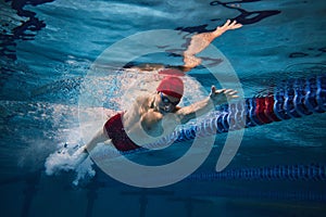 Powerful strokes. Freestyle swimming type. Young man, swimmer in motion training in swimming pool