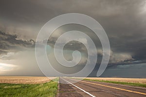 A powerful supercell thunderstorm looms over the highway.