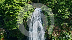 Powerful waterfall falling tropical forest. Drone shot of raging water flowing