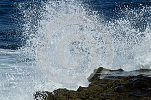 Powerful wave crashing on a rock in the ocean