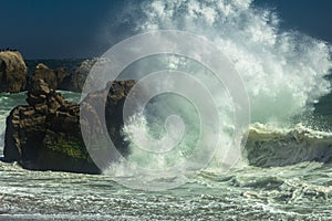 Powerful wave crashing on the rocks at a beach in Malibu