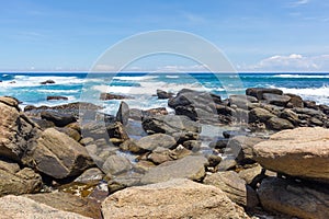 A powerful wave with splashes and foam breaks on a rocky shore. Sri Lanka