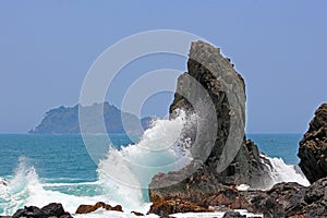Powerful waves crashing rocks in the seashore. Bright sunny day in the rocky beach