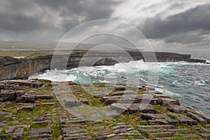 Powerful waves hist rocks at the bottom of cliff. Inishmore, Aran islands, county Galway, Ireland. Cloudy sky. Nobody. Nature photo